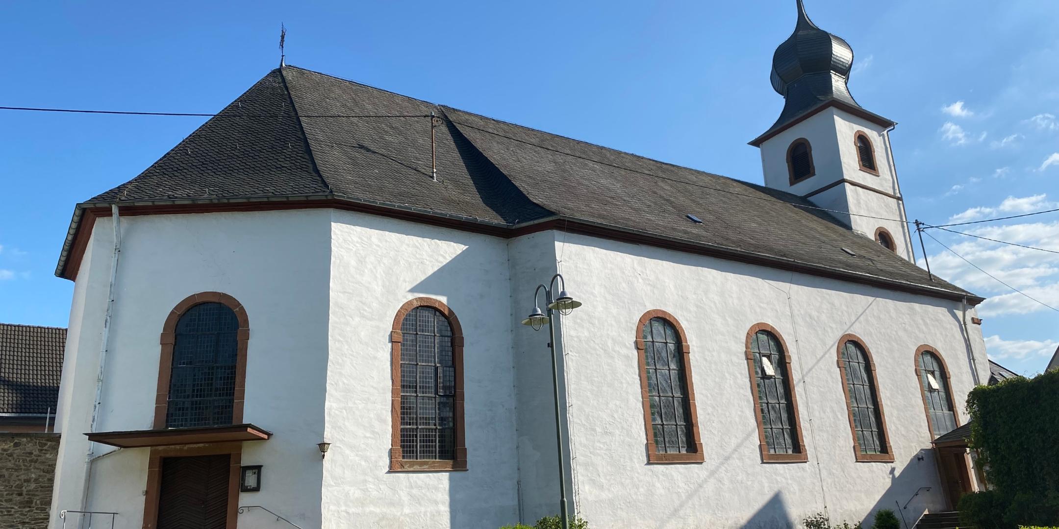 Brauneberg St. Remigius 01 - Die Simultankirche von der Moselseite aus gesehen. Links am Chorbau der Eingang in den evangelischen Kirchenraum, rechts am turmseitigen Ende des Schiffs der Eingang in den katholischen Teil.